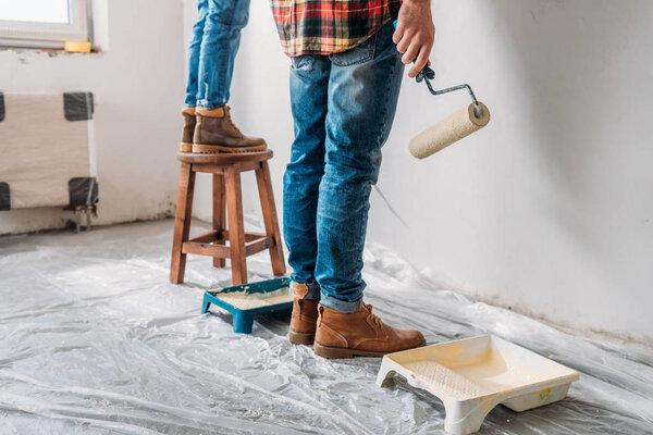 cropped shot of young couple painting wall in new apartment