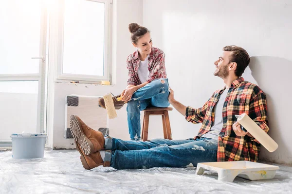 Feliz Jovem Casal Segurando Rolos Pintura Sorrindo Uns Aos Outros — Fotografia de Stock