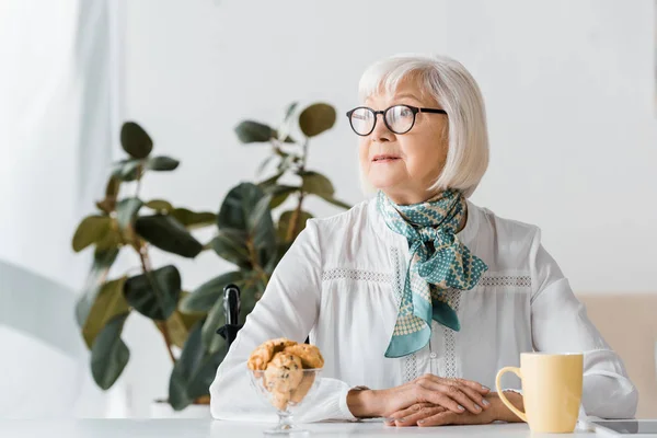 Seniorin Gläsern Sitzt Mit Tasse Und Keksen Tisch — Stockfoto