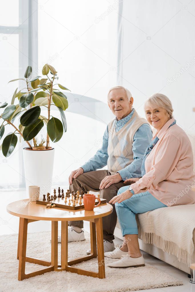 senior couple sitting on sofa and playing chess