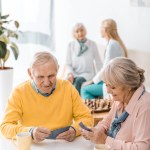 Senioren spielen Karten am Tisch im Pflegeheim