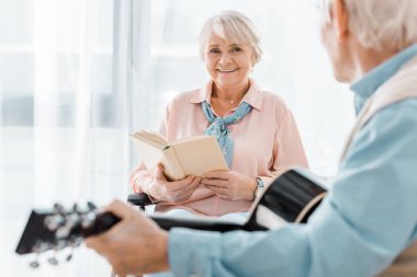üst düzey komuta sizde akustik gitar çalmaya dinlerken kitap ile gülümseyen