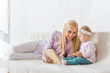 genç gülümseyen annesi okuma kitabı çerez holding toddler ise küçük kızı