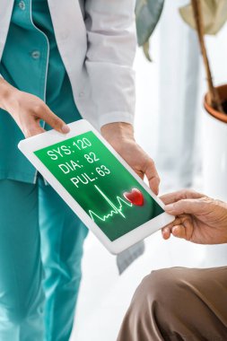 Doktor ve hasta ellerini dijital tablet kardiyogram ile ekran üzerinde tutarak yakın çekim