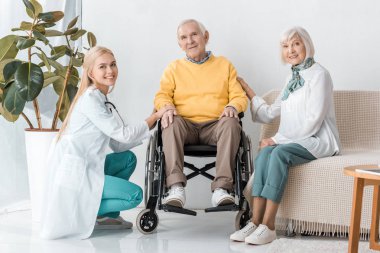 young female doctor sitting with senior patients in clinic clipart