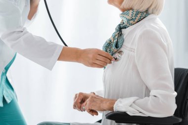 bir genç kadın doktor stetoskop ile kadın Engelli kıdemli inceleyerek yakın çekim 