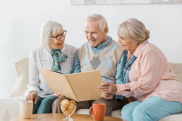 Senior Smiling People Sitting Sofa Reading Book Together — Stock Photo, Image