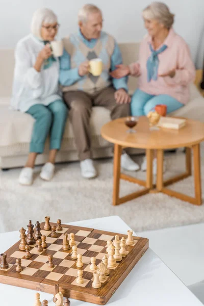 Dřevěné Šachy Stůl Postavami Rozmazané Starších Lidí Pozadí — Stock fotografie