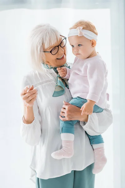 带着眼镜抱着小孙女的外婆面带微笑 — 图库照片