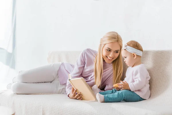 Young Smiling Mother Reading Book Small Daughter While Toddler Holding — Stock Photo, Image