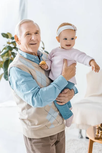 高爷爷抱着幼儿孙女与饼干 — 图库照片