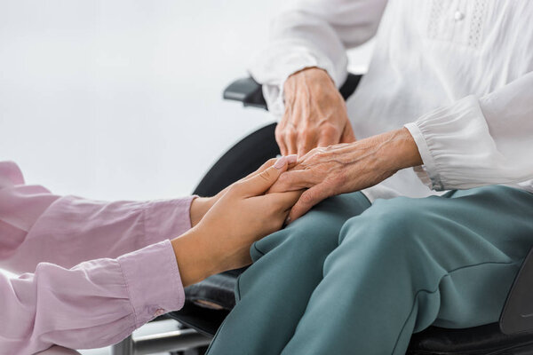 young and senior women holding hands in nursing home
