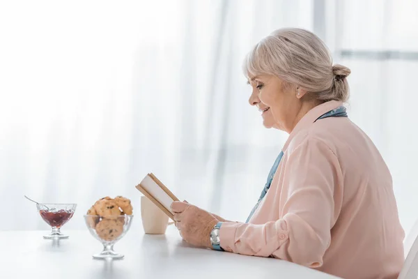 Senior Woman Sitting Table Reading Book Nursing Home — Free Stock Photo