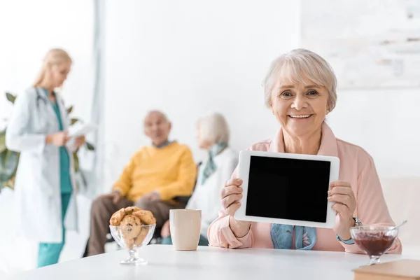 Starší Žena Ukazuje Černou Obrazovku Digitálním Tabletu Nemocnici — Stock fotografie