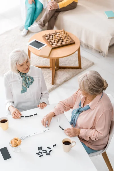 特別養護老人ホームで白いテーブルでドミノをプレイするシニア女性 — ストック写真