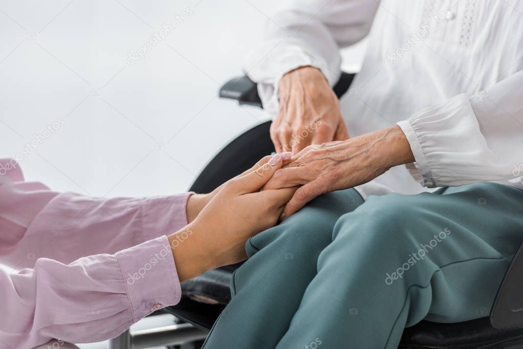 young and senior women holding hands in nursing home