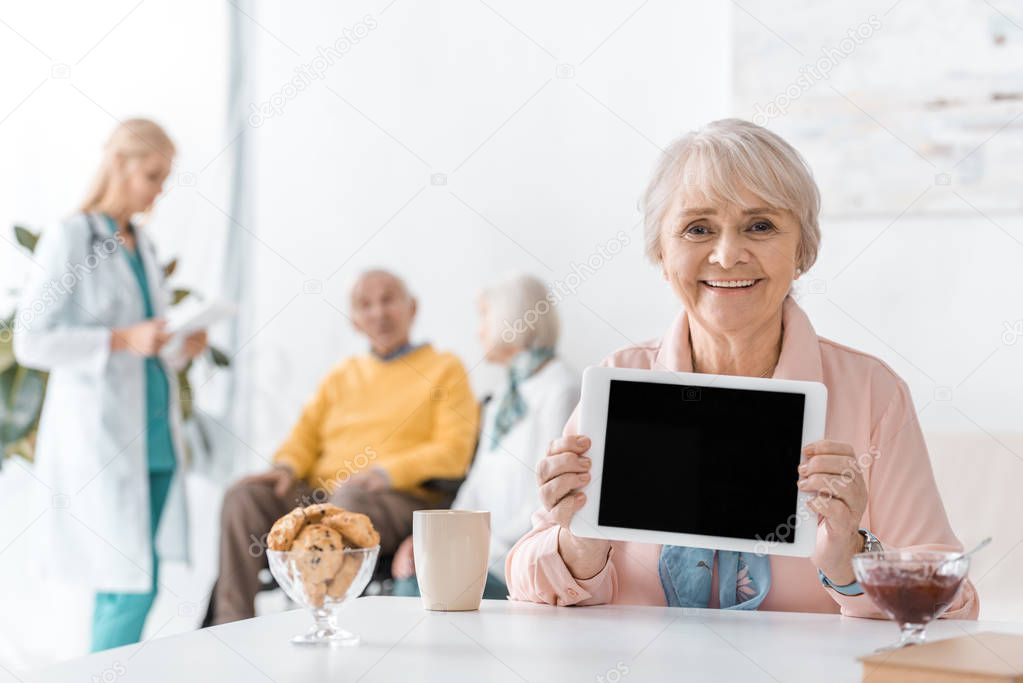 senior woman showing black screen on digital tablet at hospital