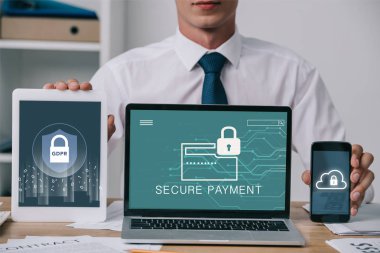 ofiste işyerinde ekranlarda işadamı dizüstü bilgisayar, tablet ve akıllı telefon gdpr ve siber güvenlik ile gösterilen kırpılmış atış işaretleri