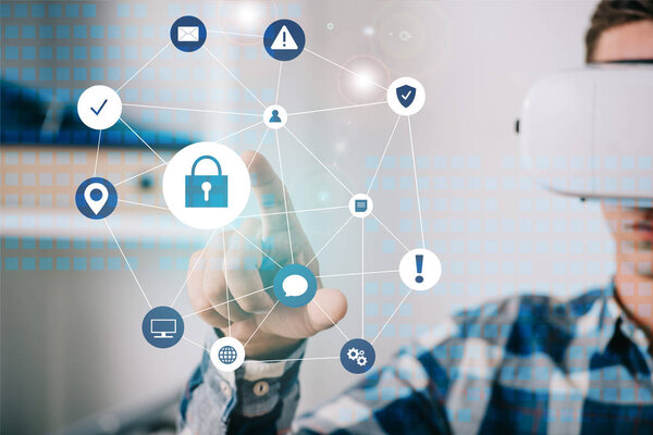 человек в гарнитуре виртуальной реальности, указывающий на знаки кибербезопасности в комнате
