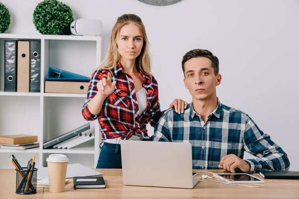 businessman looking at female colleague gesturing at workplace in office