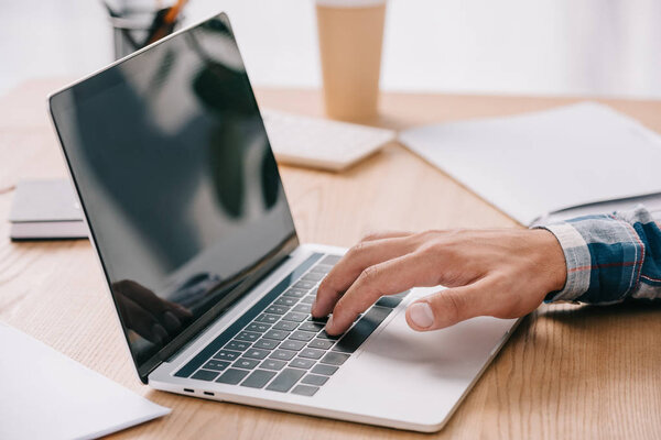 cropped shot of businessman typing on laptop while taking part in webinar