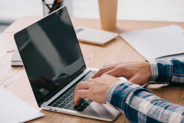cropped shot of businessman typing on laptop while taking part in webinar
