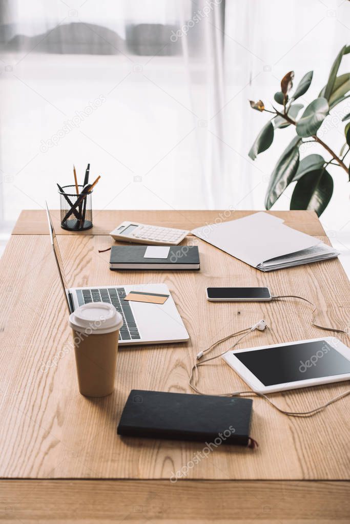 close up view of workplace with laptop, coffee to go and notebook