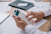 Oříznout záběr podnikatelka dělat výpočty na kalkulačce na pracovišti s dokumenty