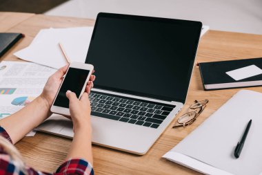 dizüstü bilgisayar ve kağıtları işyerinde smartphone kullanarak işkadını kadeh kırpılmış