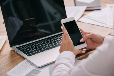 workpalce dizüstü bilgisayar ile smartphone kullanarak işkadını kadeh kırpılmış