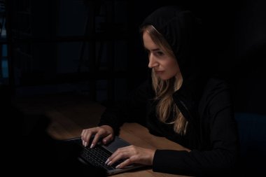 kadın siyah hoodie, siber güvenlik konsept dizüstü bilgisayar kullanarak yan görünüm