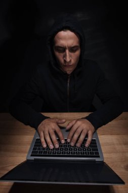 ahşap masa üstü, cuber güvenlik kavramı dizüstü kullanarak siyah hoodie odaklı hacker