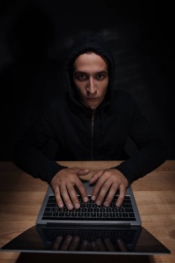 Kamera dizüstü bilgisayar, cuber güvenlik kavramı kullanırken seyir siyah hoodie hacker portresi