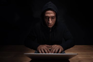 konsantre hacker siyah hoodie cuber güvenlik kavramı, dizüstü bilgisayar kullanarak'portresi