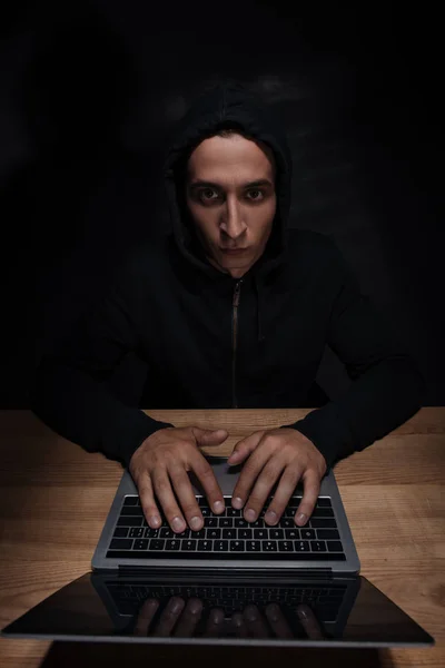 Portret Hacker Czarnym Kapturem Patrząc Kamery Podczas Korzystania Laptopa Koncepcja — Zdjęcie stockowe