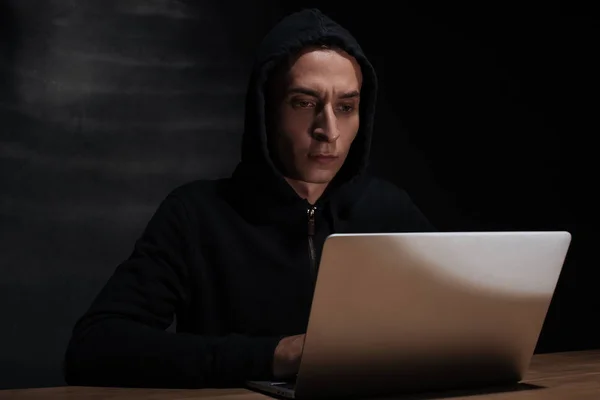 黑毛黑客的肖像在黑色连帽使用笔记本电脑 立方体安全概念 — 图库照片