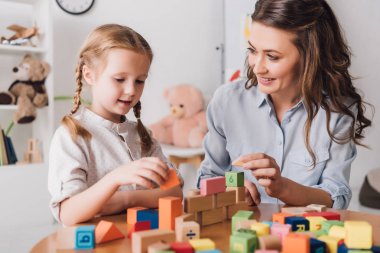 happy mother playing blocks with adorable little child clipart