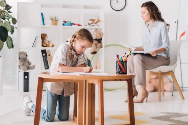 küçük çocuk ise arka plan üzerinde bulanık psikolog oturma Pano ile çizim