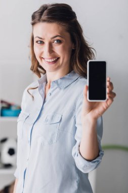 kameraya smartphone boş ekran ile gösterilen gömlekli mutlu yetişkin kadın