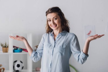 Yetişkin kadın omuzlarında shrugging gülümseyen ve kameraya bakıyor
