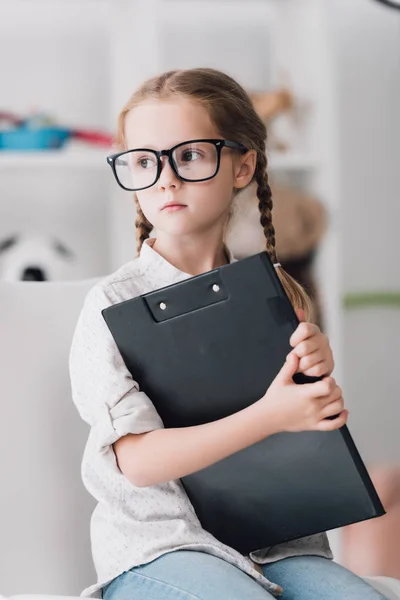 Kleines Kind Mit Brille Hält Klemmbrett Der Hand Und Schaut — kostenloses Stockfoto