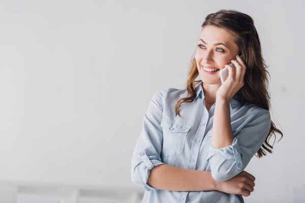 close-up portrait of smiling adult woman talking by phone and looking away