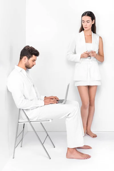 Erwachsener Mann Ganz Weiß Mit Laptop Während Stilvolle Frau Auf — kostenloses Stockfoto