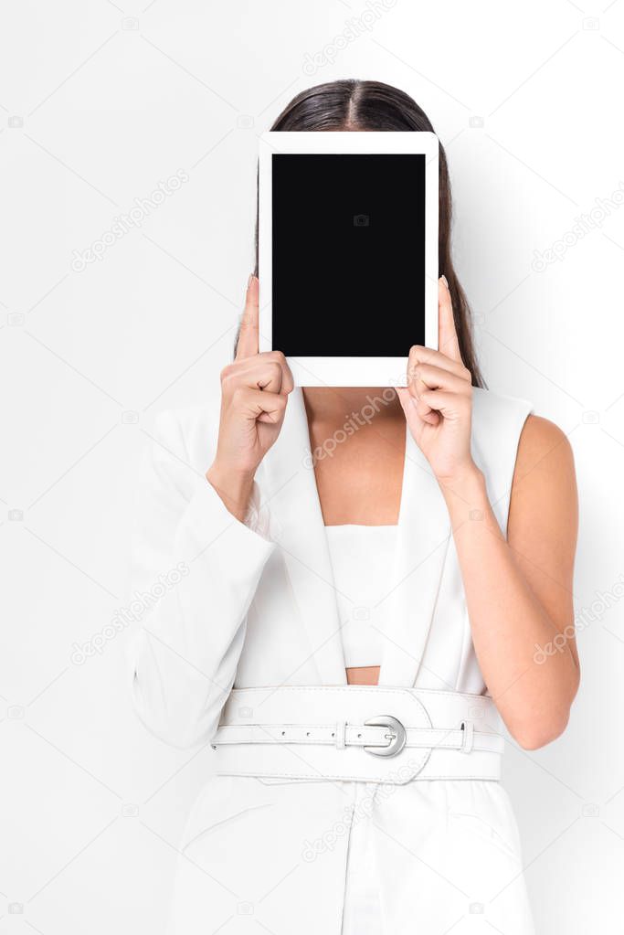 woman in total white with obscure face holding digital tablet with blank screen isolated on white