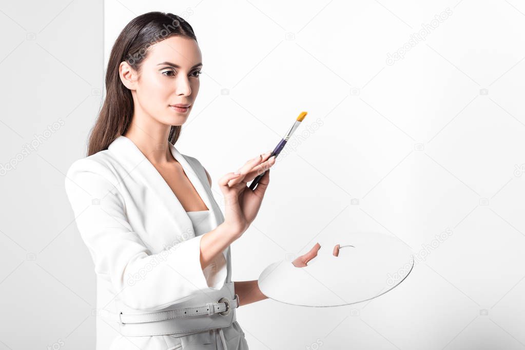 adult beautiful woman in total white posing with palette and paintbrush