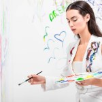 Close up of beautiful woman in total white posing with drawing equipment