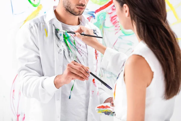 close up of adult couple drawing on clothes against painted wall