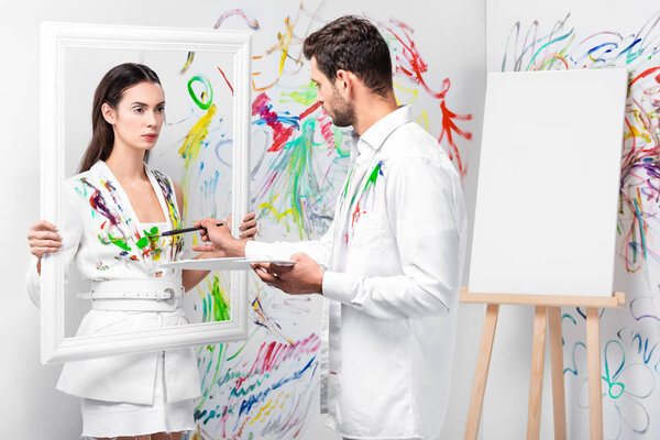 adult man drawing on woman white clothes with paintbrush