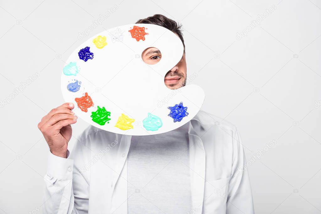 close up of man in total white holding palette with paint