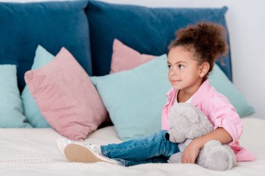 Yatakta onun oyuncak ayı ile şirin Afro-Amerikan çocuk seatting